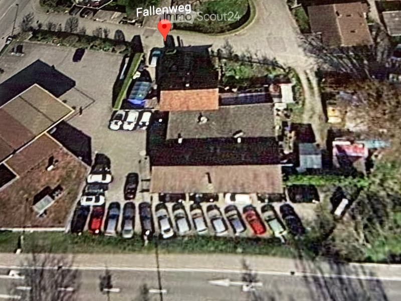 Aerial view of a multi-building complex with parking lot, several structures, and surrounding greenery.