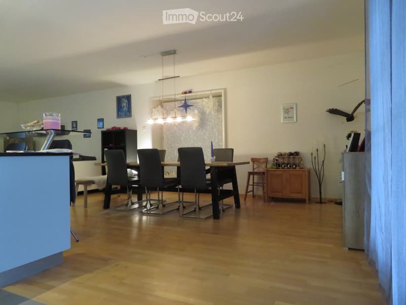 Dining area with wooden floor, modern dining table, chairs, and a small cabinet with decorative items.