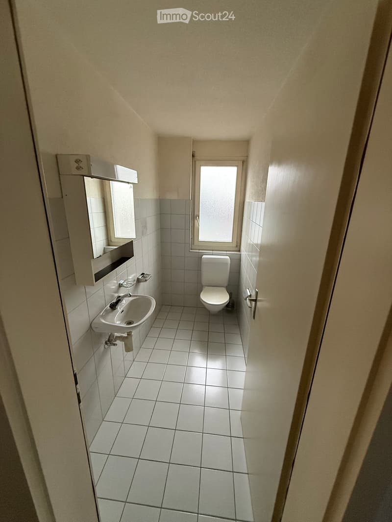 Bathroom with toilet, sink, and mirror.