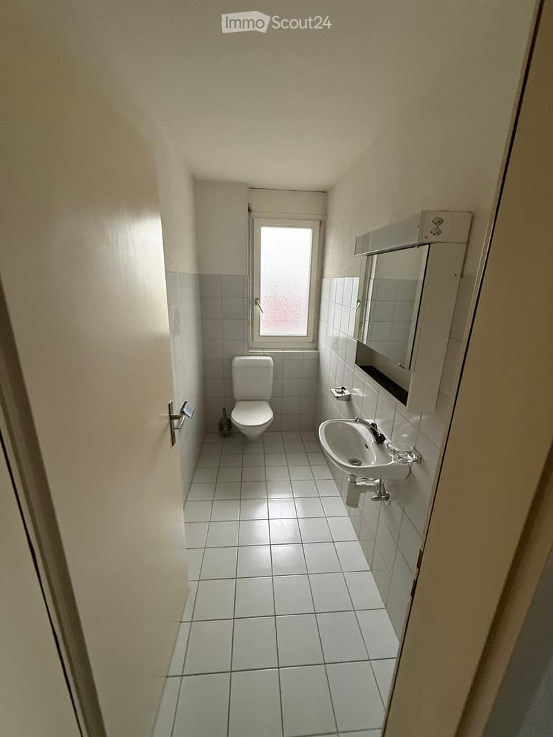 Small bathroom with toilet, sink, and window