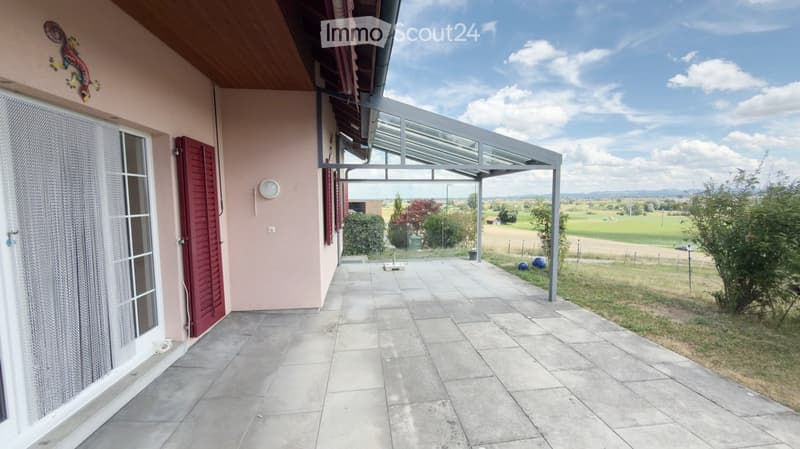 Balcony with tiled floor, glass roof structure, and scenic countryside view.