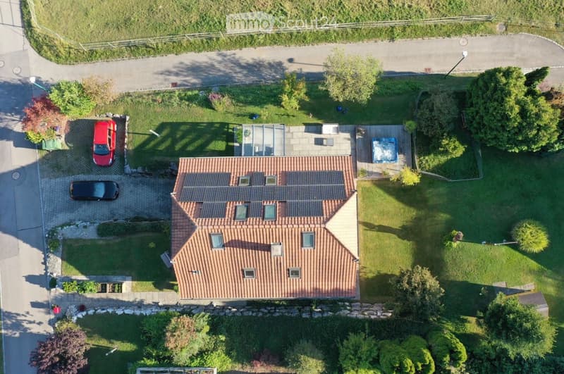 brown tiled roof, red facade, two cars parked, solar panels, swimming pool, garden, garage