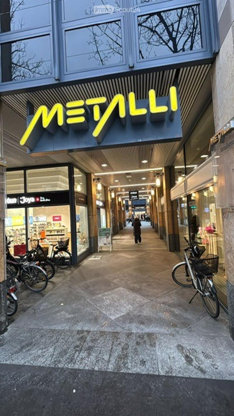 Shop entrance, signboard, bicycles parked, pathway, shop windows, people walking