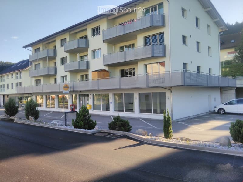 4-story apartment building, balconies, 2 cars parked, garden in front