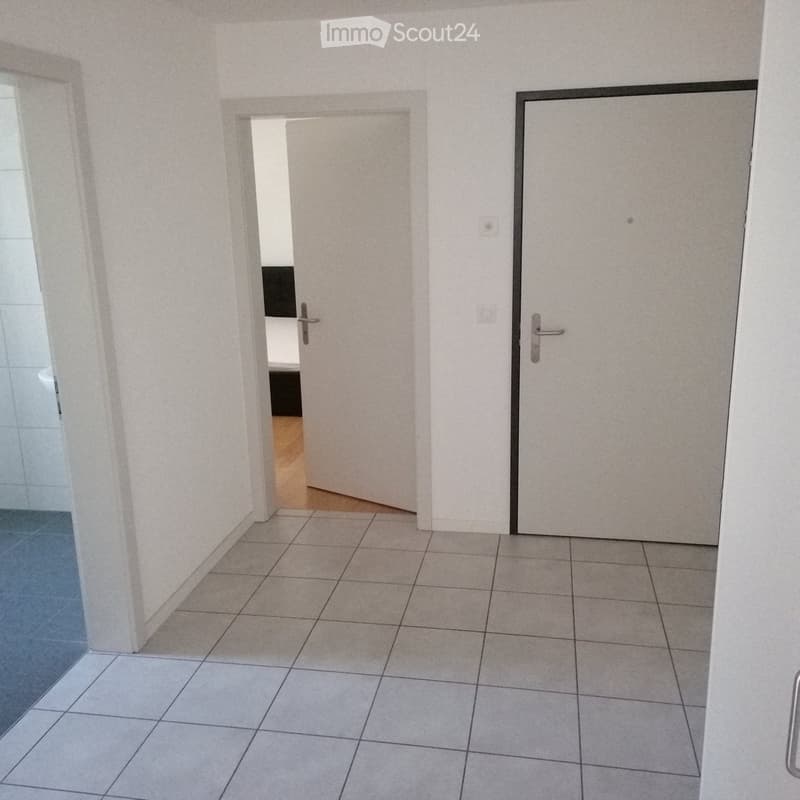 Empty hallway with tiled floor, white walls, and two doors leading to other rooms.