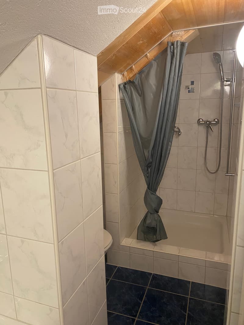 Modern bathroom with marble tiles, a glass-enclosed shower area, and a dark blue tiled floor.