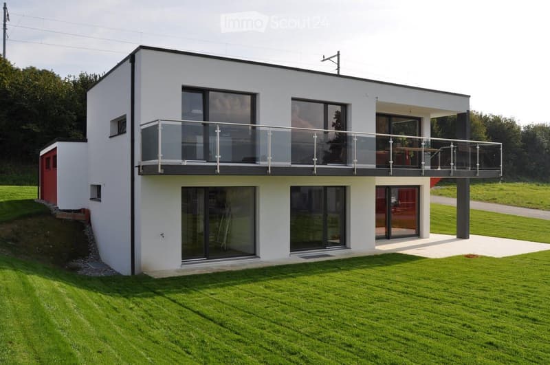 modern white house, glass windows, glass balcony, red door, large green lawn