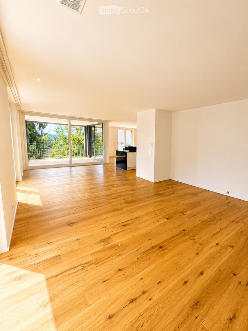 Empty room with light wooden flooring, white walls, and large sliding glass doors leading to a balcony.
