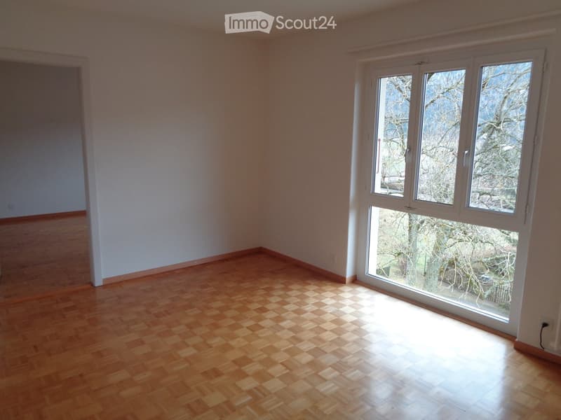 empty room with wooden floor, white walls, large windows, view of outside