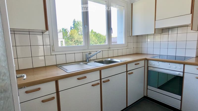 Modern kitchen with white tiled walls, wooden countertops, stainless steel sink, and built-in oven.