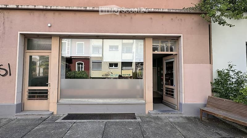 Facade of a commercial building with glass storefront and entrance, adjacent to a wooden bench.