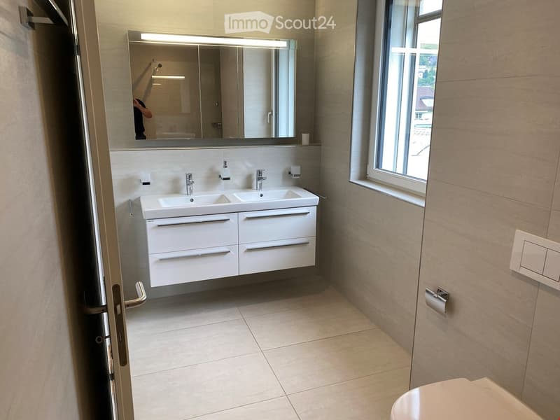 Modern bathroom with double sink, large mirror, and white cabinetry.