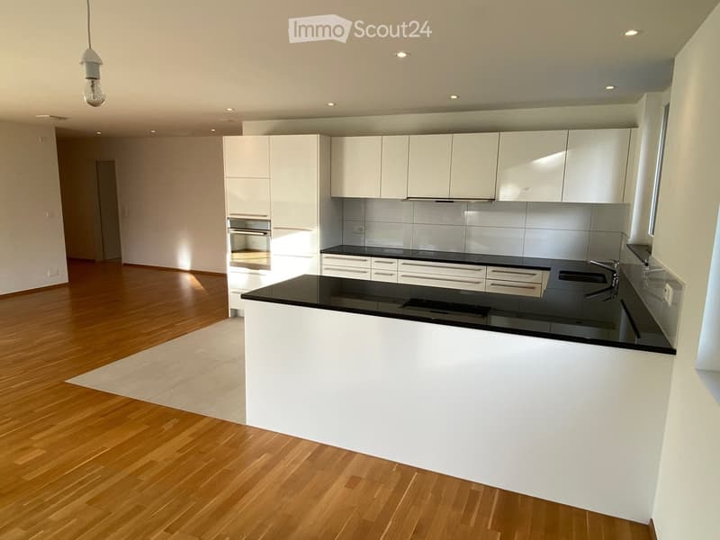 Modern kitchen with white cabinets, black countertops, and a central island. Features include a built-in oven, sink, and ample storage space.