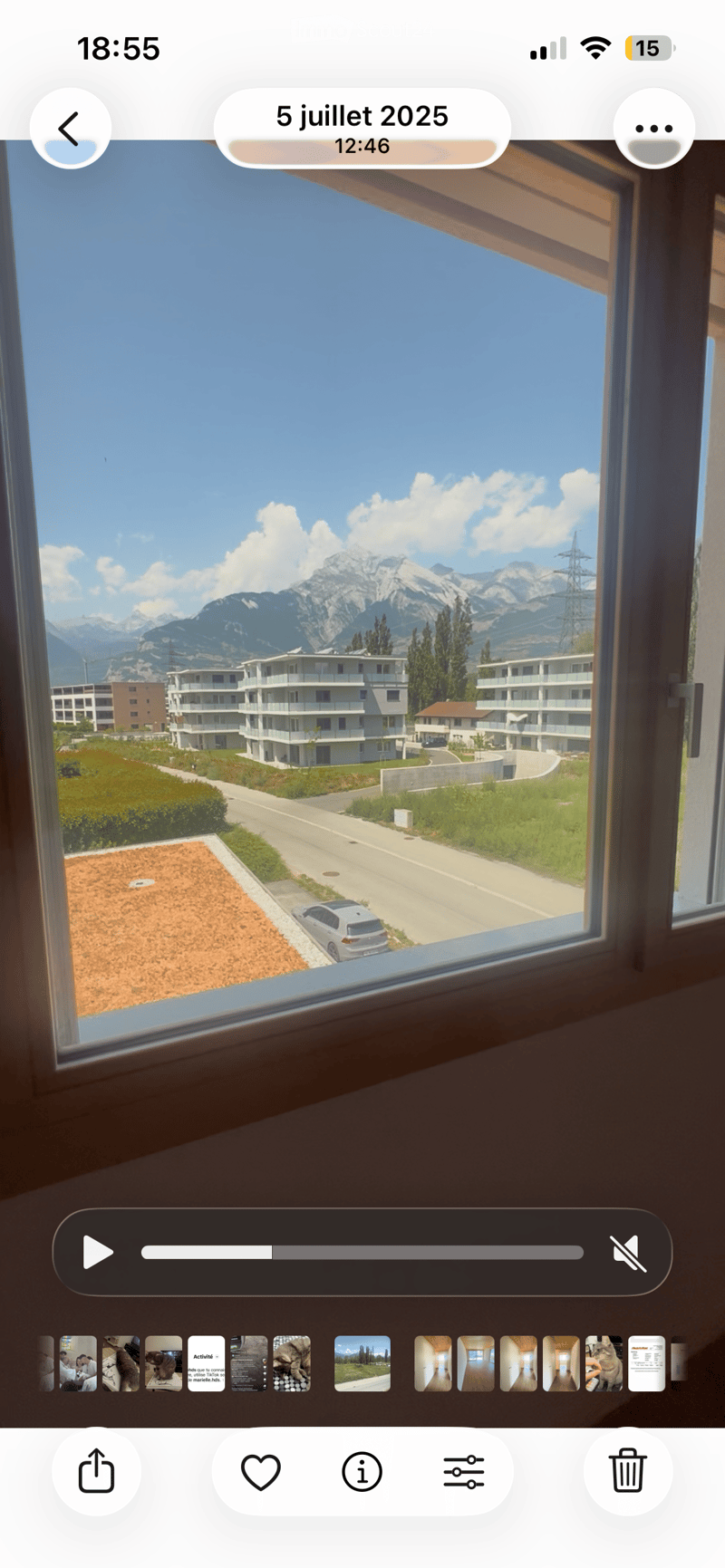 View from a balcony showing a clear blue sky, distant mountains, and a residential area with buildings and a road.
