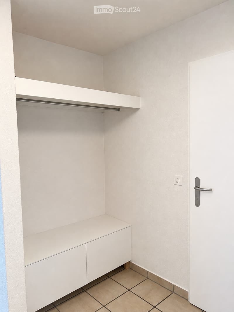 Empty closet with white built-in shelving and a closed door.