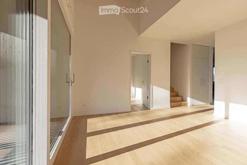 empty room with hardwood floors, large glass door, open door leading to staircase, large white walls