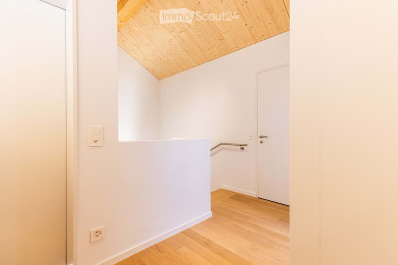 white walls, wooden floor, small window, two power outlets, white doors