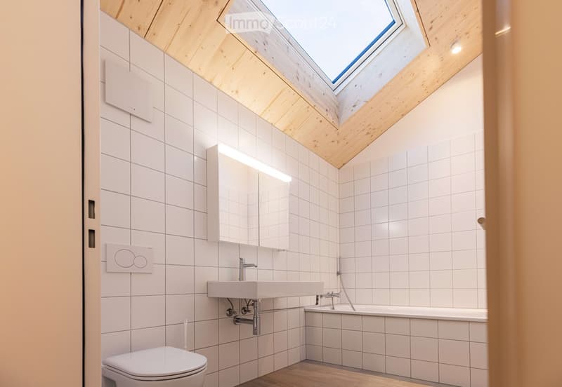 white tiled walls, wooden ceiling, modern fixtures, skylight, white toilet, white bathtub, white sink