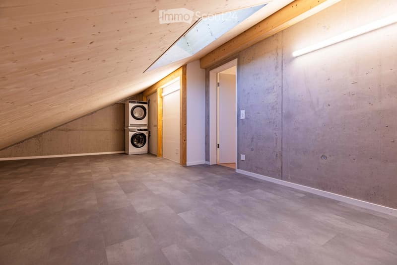 a room with wooden ceiling, gray tiled floor, concrete walls, two washing machines