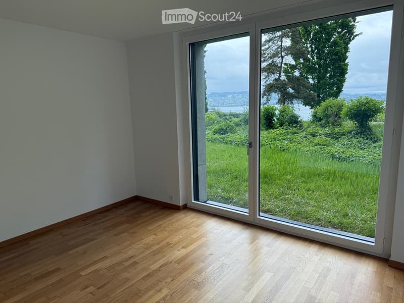 Empty room with wooden flooring and large sliding glass doors opening to a grassy outdoor area.