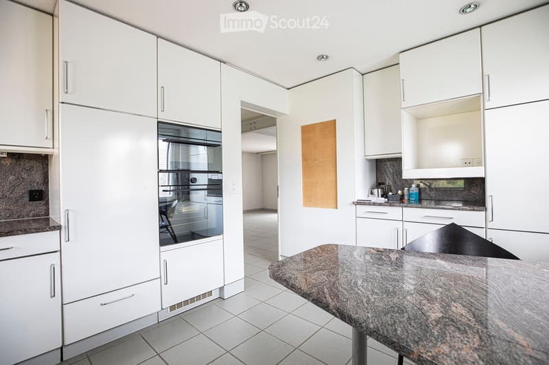 Modern kitchen with white cabinets, granite countertop, built-in oven, and various appliances.
