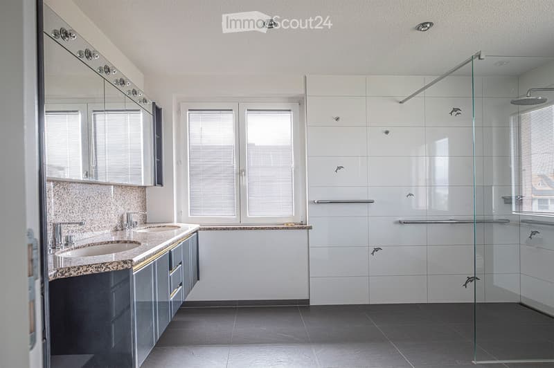 Modern bathroom with a double sink, large mirror, glass-enclosed shower, and white tiled walls.