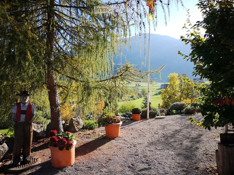 Garden area with gravel pathway, potted plants, decorative statue, and scenic mountain view.