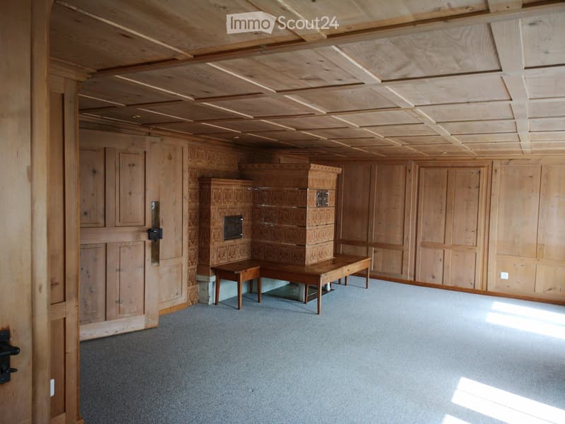 Wooden-paneled room with exposed wooden ceiling beams, a small table, a bench, and built-in cabinets.
