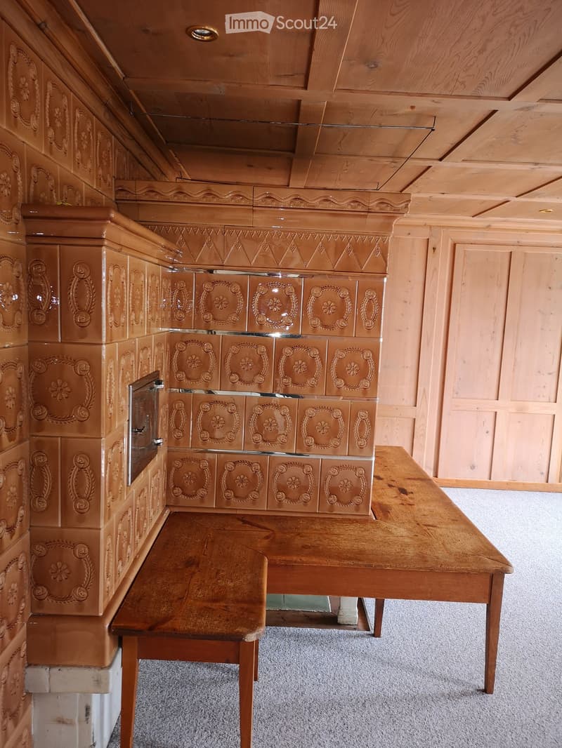 Wooden bench and table in a room with paneled walls and ceiling, featuring ornate wooden cabinetry with floral designs.