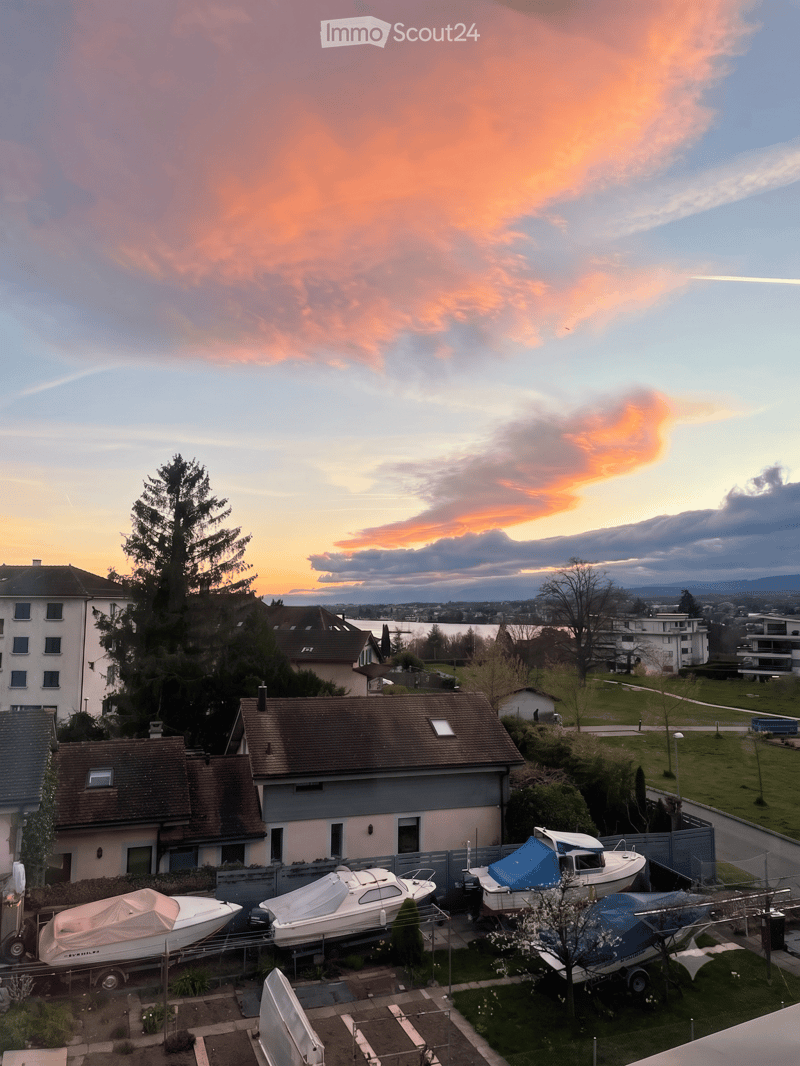 Balcony view overlooking a residential area with houses, boats on trailers, and a scenic sunset sky.