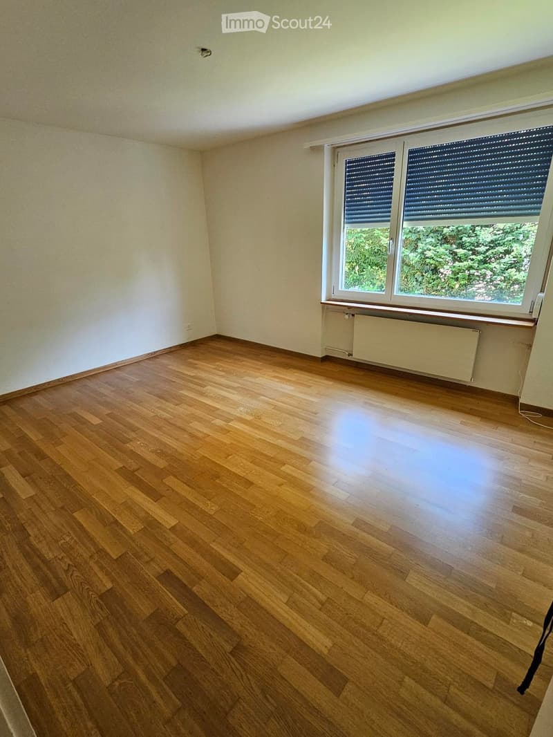 Empty room with wooden flooring, white walls, and a large window with blinds. No furniture or equipment is present.
