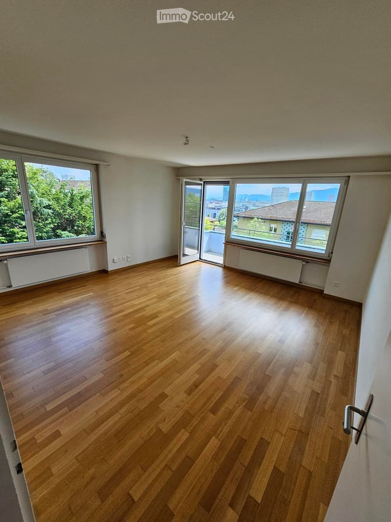 Empty room with wooden flooring, large windows, and an open door leading to a balcony.