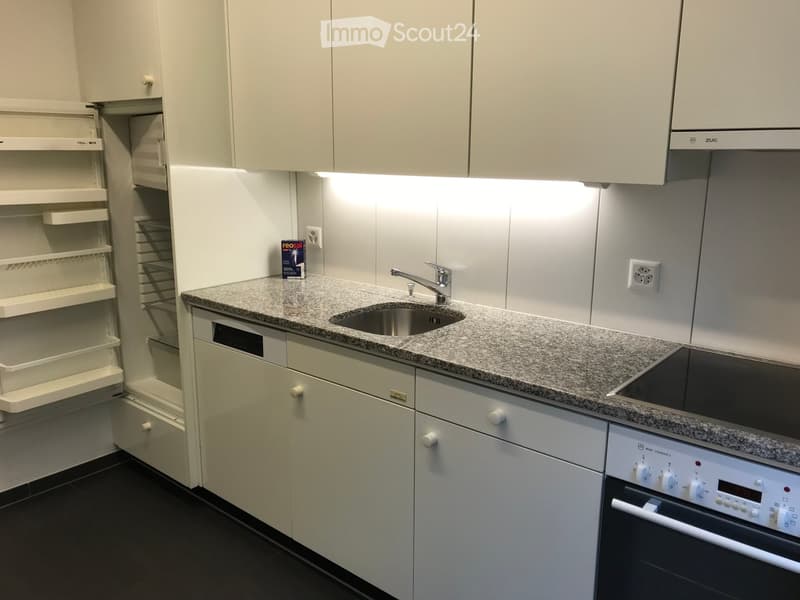 Modern kitchen with white cabinets, granite countertop, stainless steel sink, and built-in appliances including an oven and dishwasher.