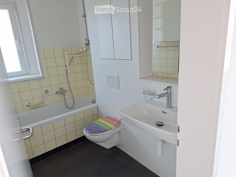 Bathroom with a bathtub, toilet, sink, mirror, and two cups on the sink counter.