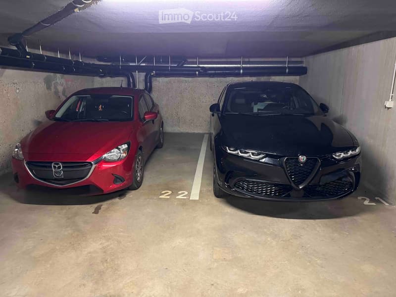 Underground parking area with two cars parked in designated spots, marked with numbers 21 and 22.