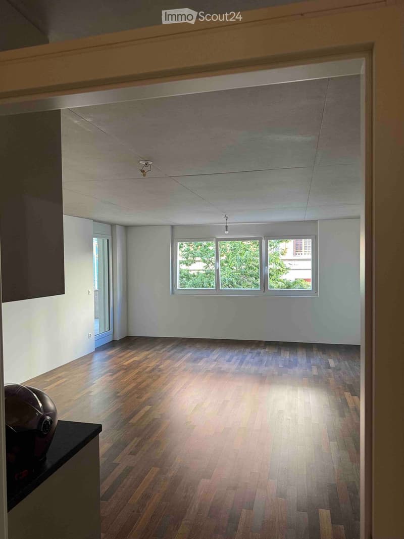 Empty room with wooden flooring, white walls, and large windows letting in natural light. No furniture or equipment present.