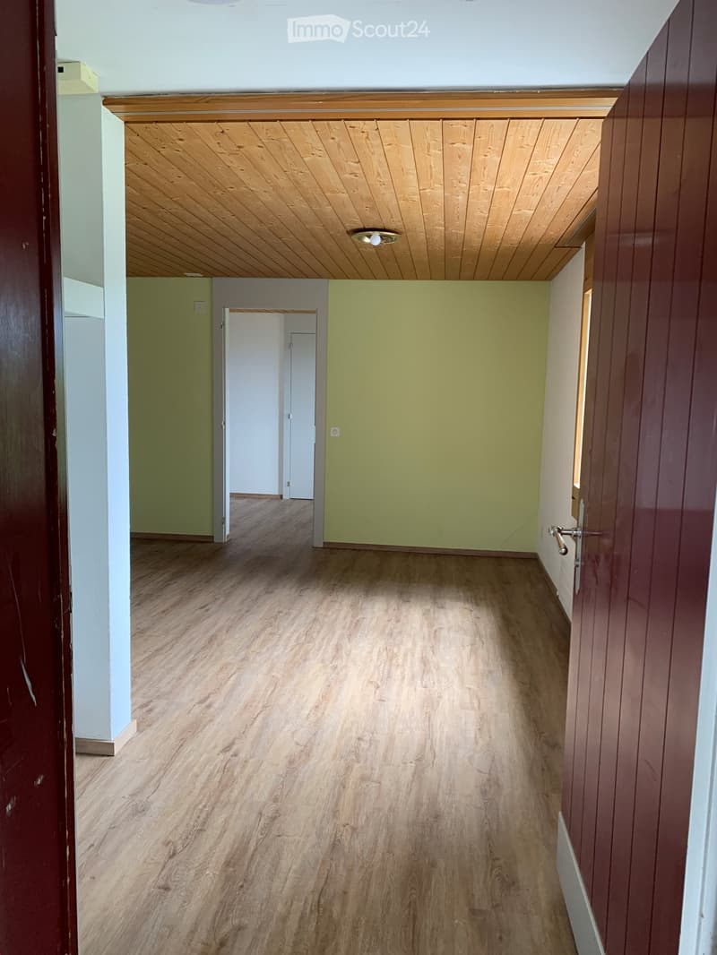 Empty hallway with wooden flooring, light green walls, and a wooden ceiling with recessed lighting. Doors lead to adjacent rooms.
