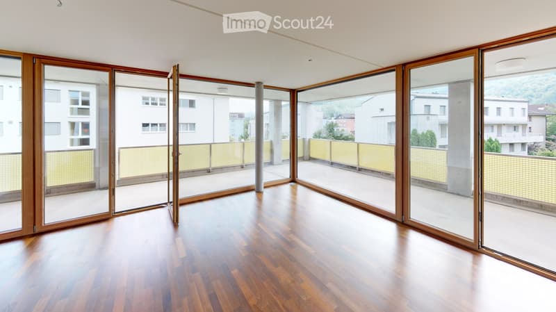 Empty room with wooden flooring and large sliding glass doors leading to a balcony area.