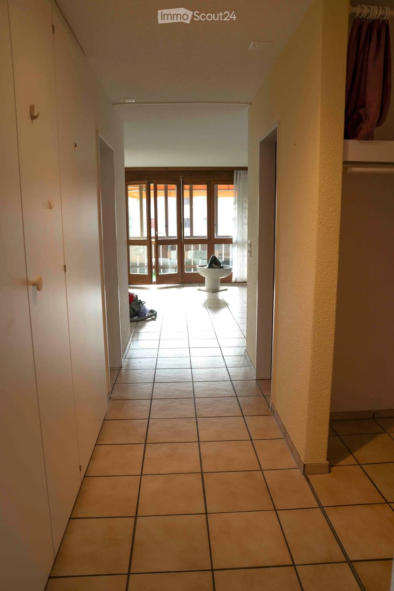 Hallway with tiled floor, wooden doors, closets, and an outdoor balcony with glass doors.