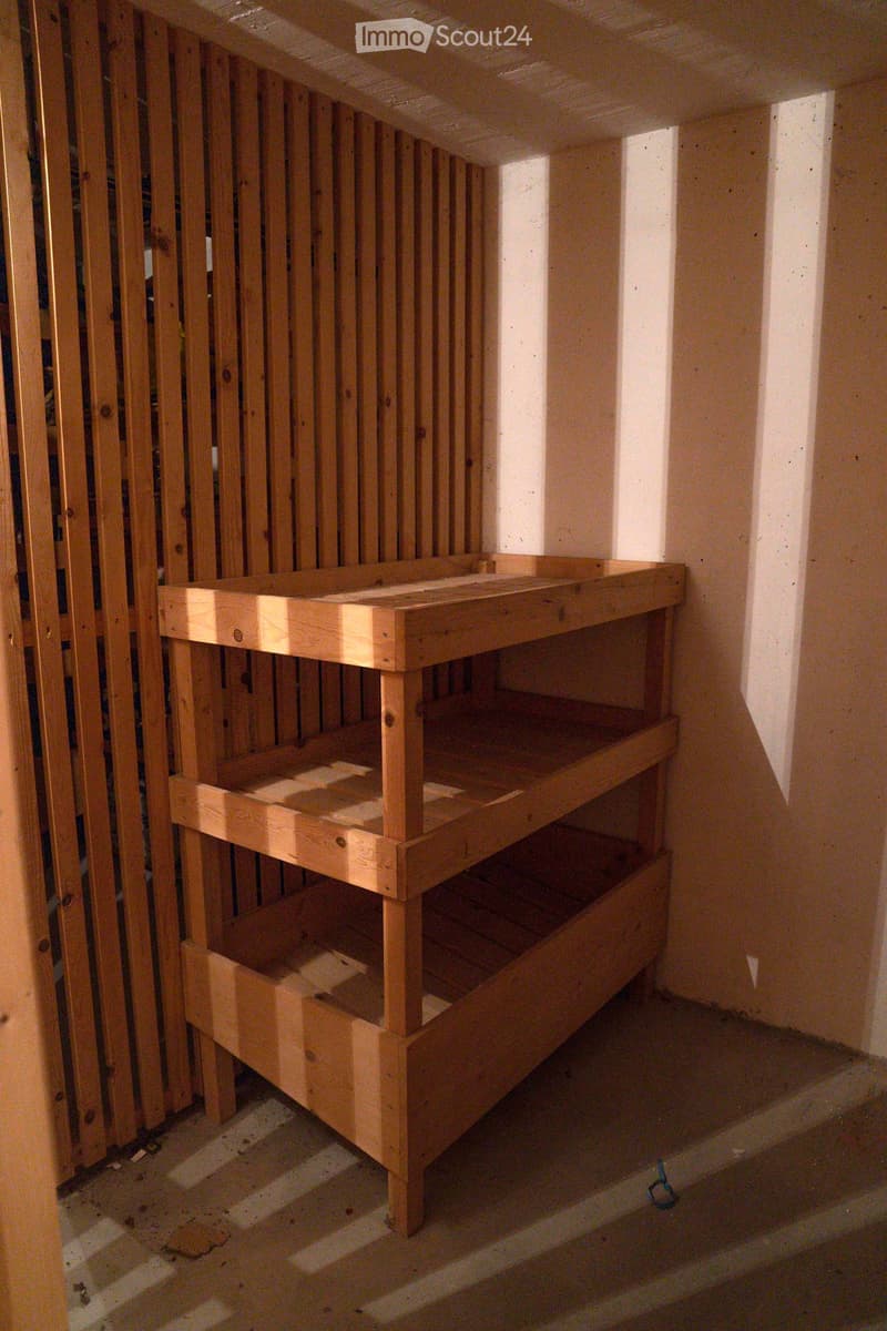 Small room with a wooden storage unit and wooden slats on the wall.