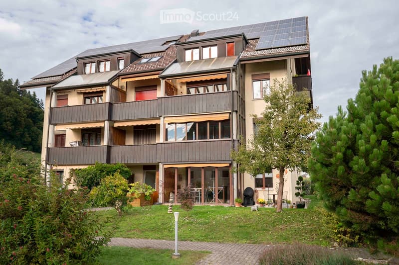 3 story apartment, brown roof, white walls, solar panels, small garden, balcony