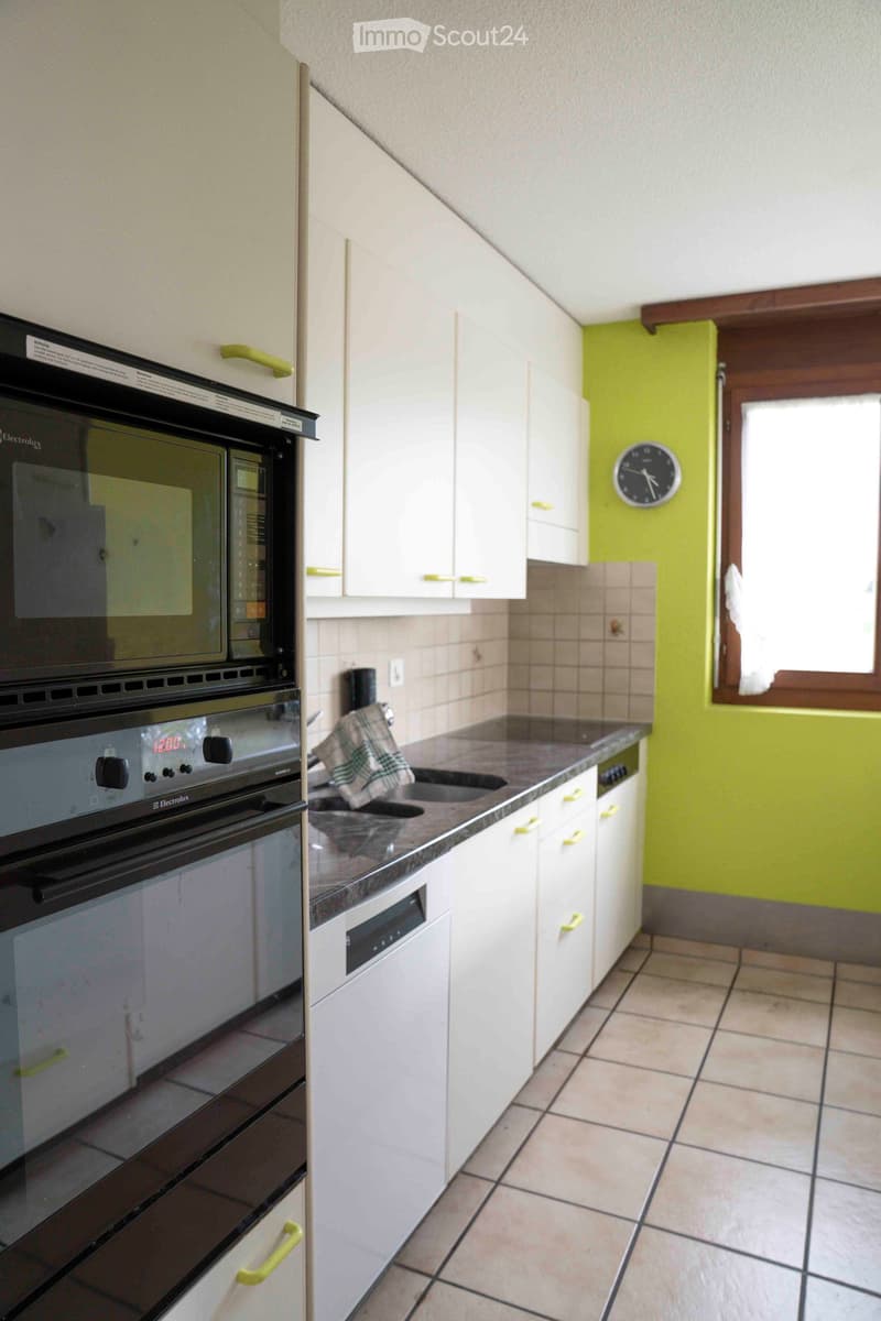 white kitchen, double oven, sink, countertop, kitchen cabinets, clock, green wall