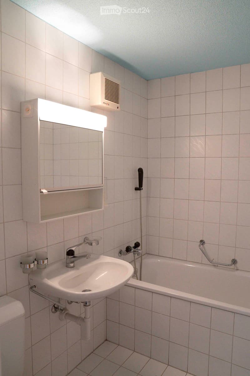 bathroom with white tiles, sink, bathtub, shower, mirror, light fixture