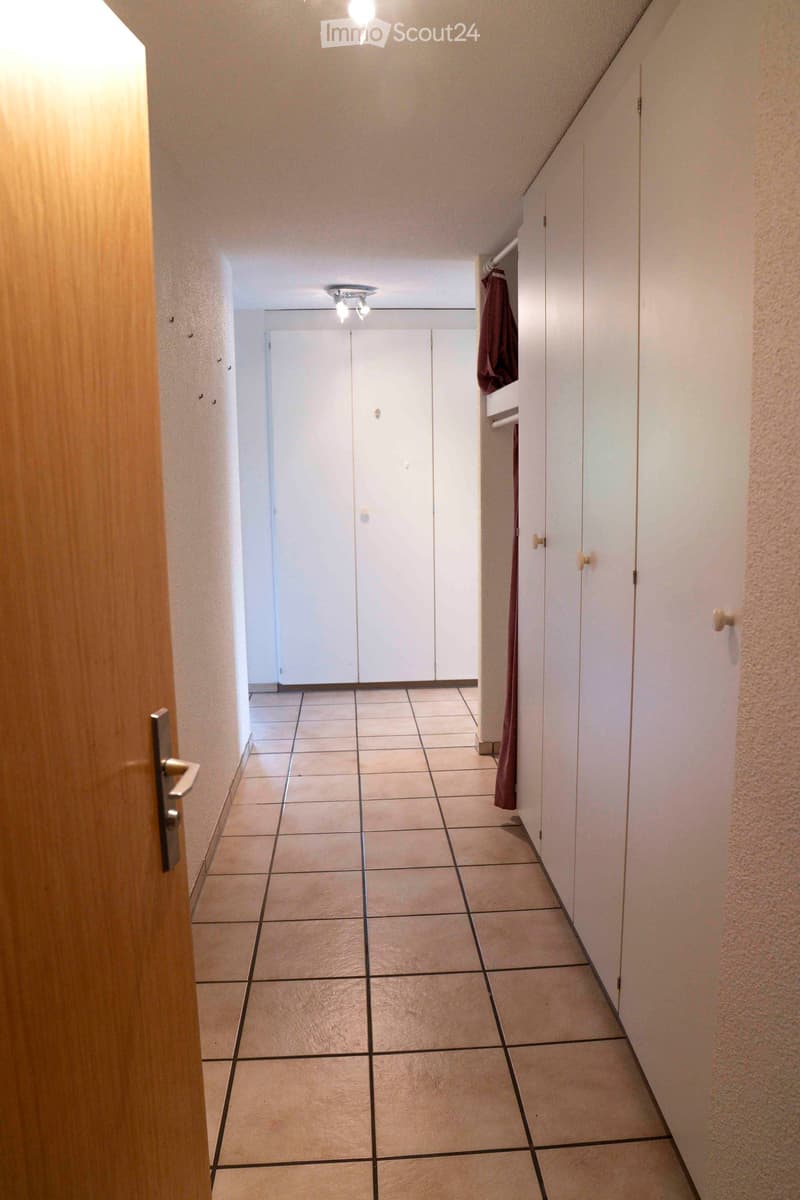 Empty corridor with tiled flooring, large closets on both sides.