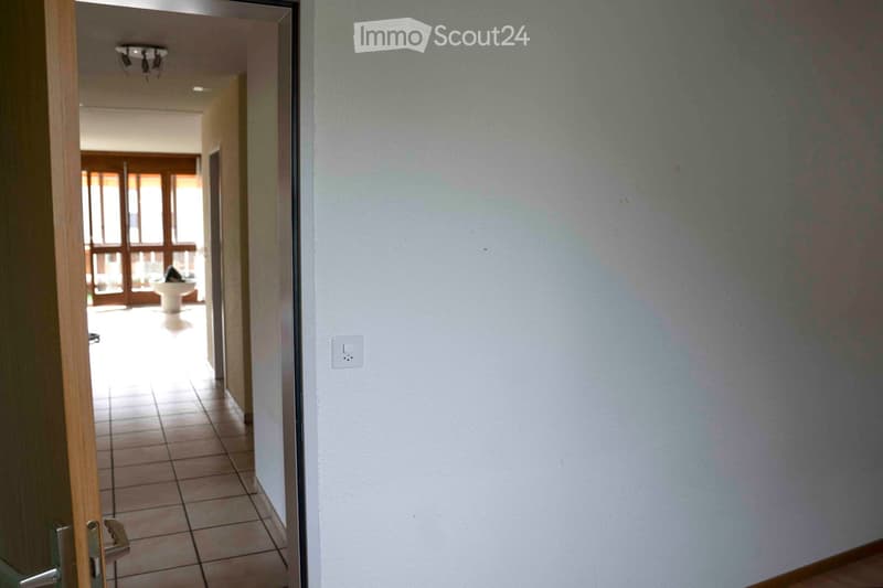 tiled floor, hallway leading to the bathroom, wall switch, bathroom in the background