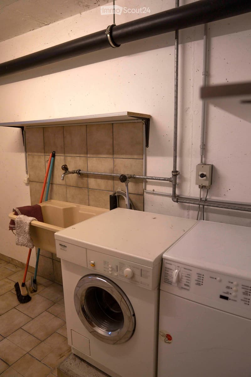 a room with a washing machine, a dryer, a sink, a faucet, and cleaning tools