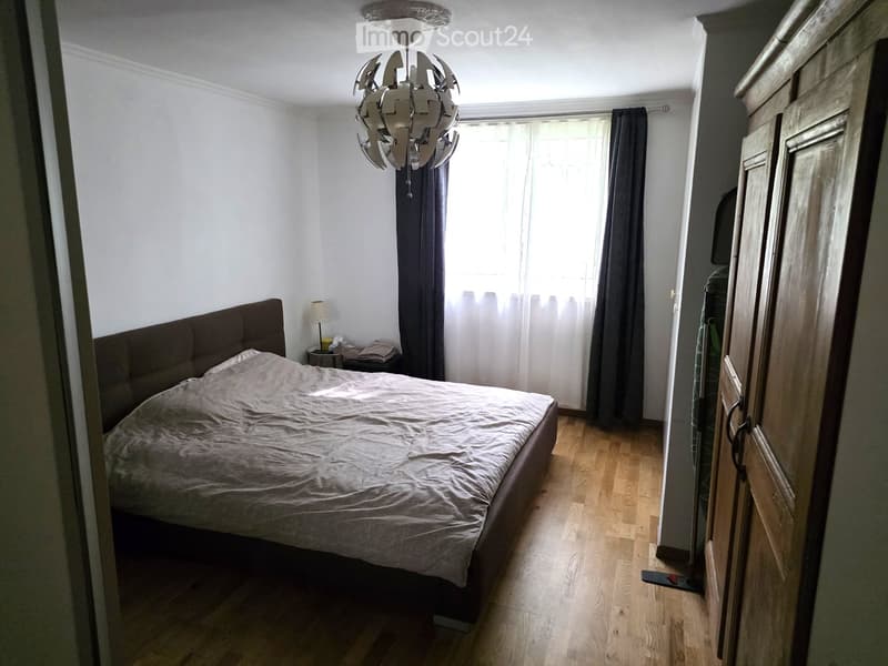 Bedroom with a large bed, nightstand, lamp, wardrobe, and a modern chandelier.