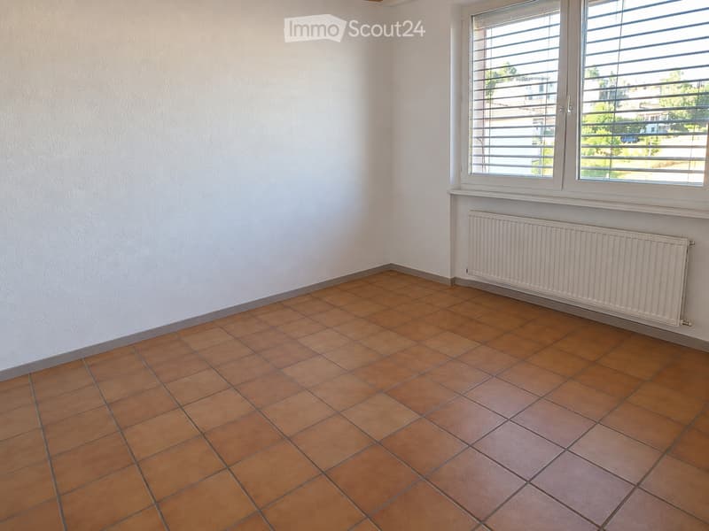 Empty room with tiled floor and white walls, featuring a window with blinds and a radiator below it.