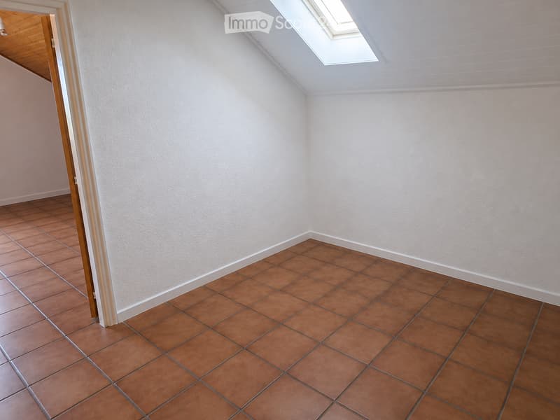 Empty room with light-colored walls, brown tiled floor, and a skylight window in the ceiling. The room has a simple, clean design with no furniture or decorations.