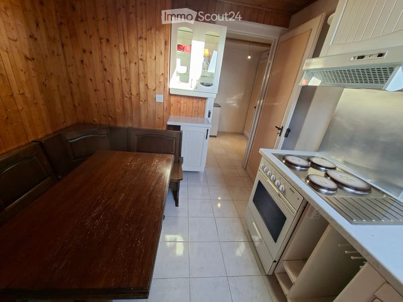Kitchen with wooden walls, tiled floor, stove, oven, table, and chairs.